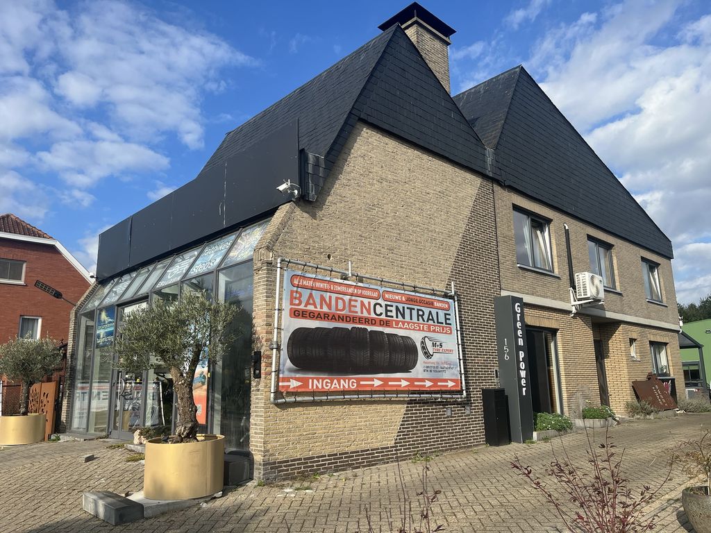 Het spandoek van M+S Tyre Expert aan de gevel in Genk, met pijlen naar de ingang